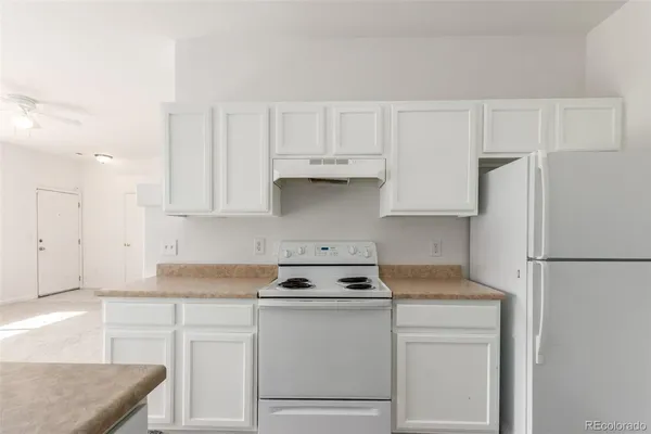 a kitchen with refrigerator a stove a white and white cabinets