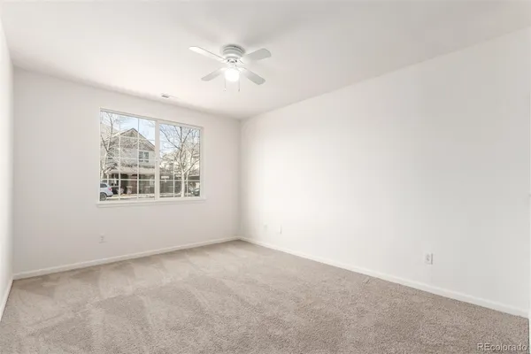 an empty room with windows and fan