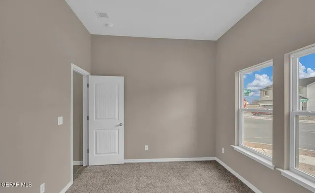 an empty room with windows and fireplace