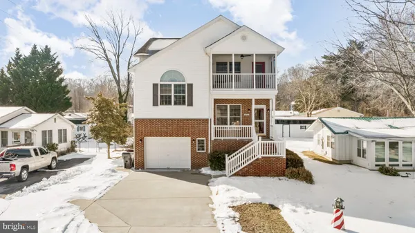 a view of a white house with a yard and parking space