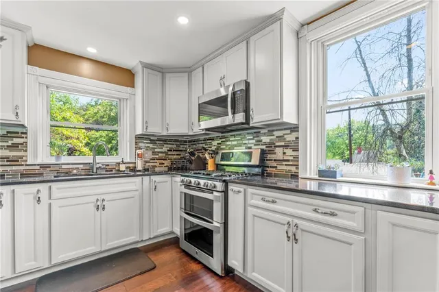 a kitchen with stainless steel appliances white cabinets and a window