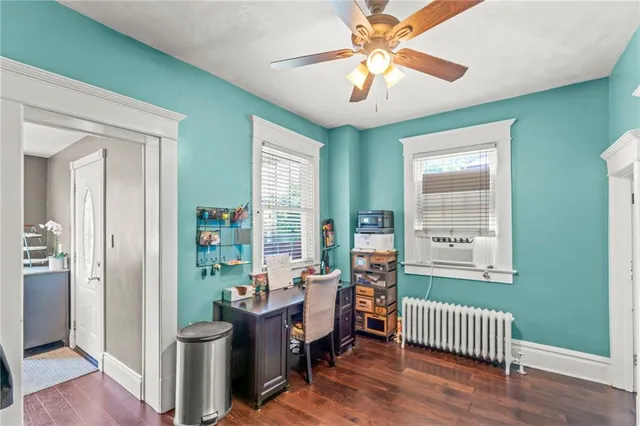an empty room with chandelier fan and windows