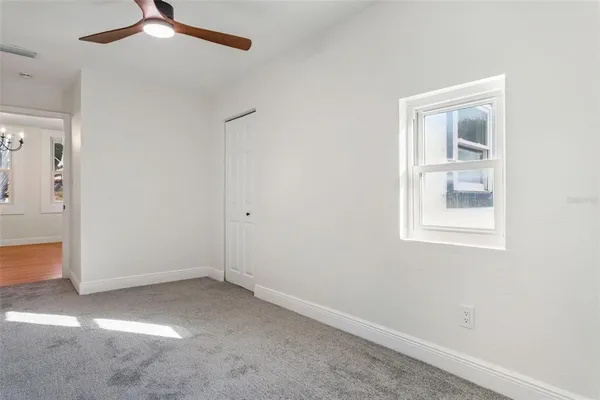 an empty room with a window and a ceiling fan