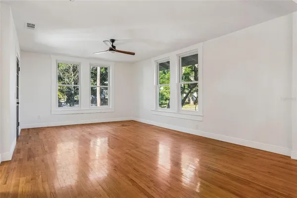 a view of an empty room with wooden floor and a window