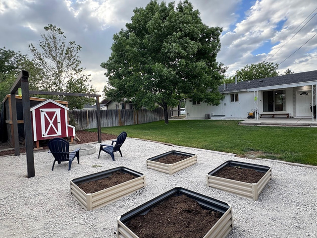 1791 West 170 South, Unit 8 Provo, UT 84601 - Photo 18 of 25 Expansive backyard with a large shade tree, multiple raised garden beds, and a pea gravel patio featuring a built-in fire pit