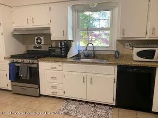 a kitchen with granite countertop white cabinets and window