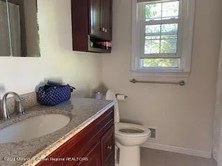 a bathroom with a granite countertop sink a toilet and a mirror