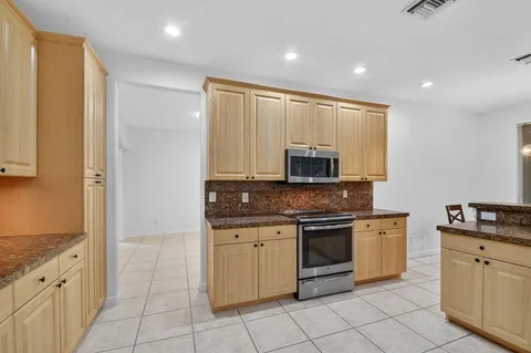a kitchen with a table chairs microwave and cabinets