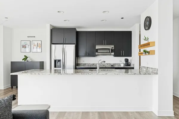 a large kitchen with kitchen island stainless steel appliances cabinets a sink and a counter top space