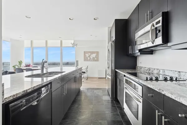 a large kitchen with stainless steel appliances granite countertop a lot of counter space and a sink