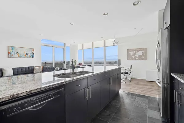 a large kitchen with kitchen island granite countertop a sink and white cabinets