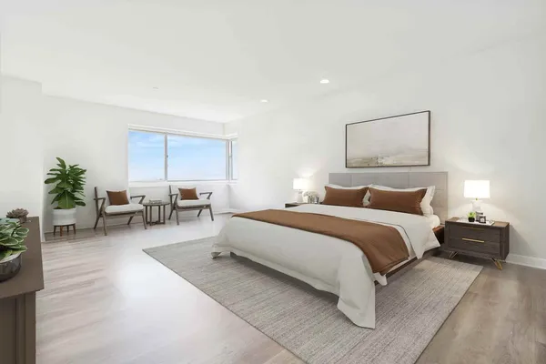 a spacious bedroom with a bed a couch and potted plant on the table