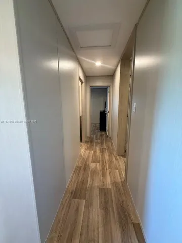 a view of hallway with stainless steel appliances wooden floor