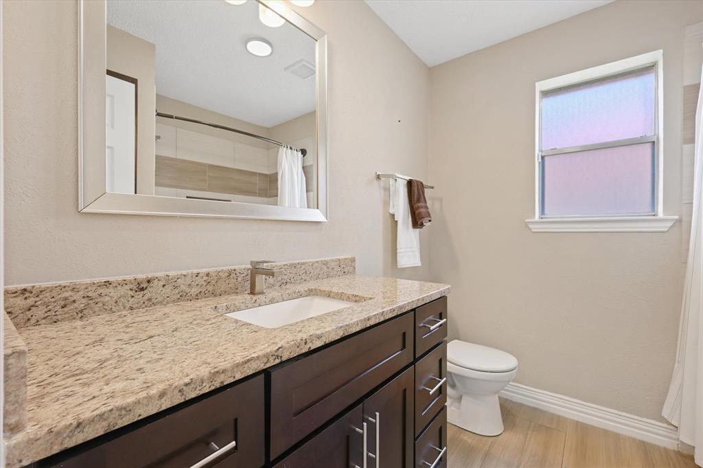 7636 Castillo Road Fort Worth, TX 76112 - Photo 18 of 28 a bathroom with a granite countertop sink a toilet and mirror