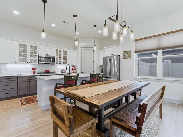 a kitchen with a stove a refrigerator a sink dishwasher with a dining table and chairs with wooden floor