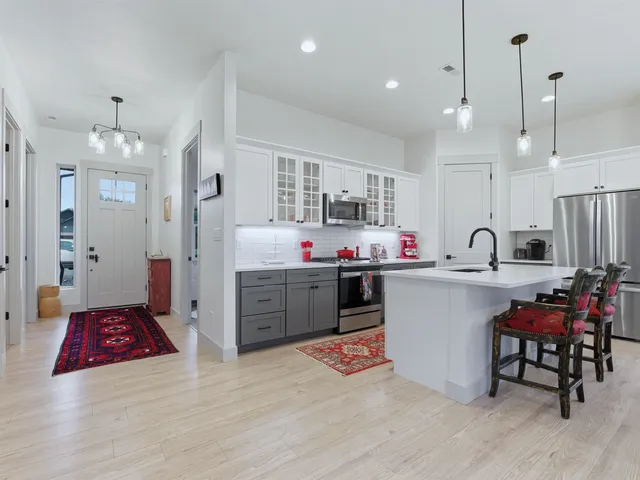 a open kitchen with stainless steel appliances kitchen island granite countertop a refrigerator a sink dishwasher a dining table and chairs with wooden floor