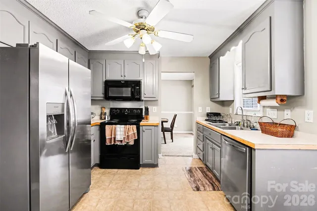 a kitchen with stainless steel appliances granite countertop a refrigerator a stove a sink a dining table and chairs