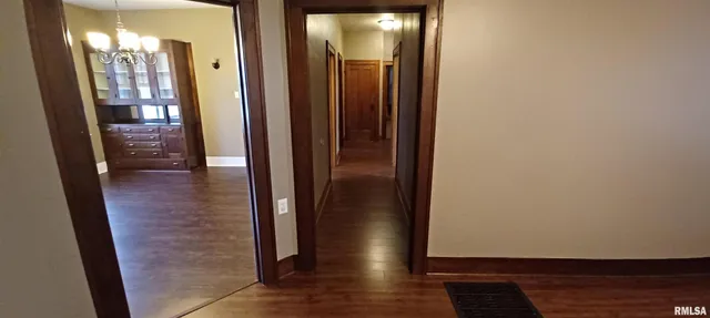 a view of a hallway with wooden floor and a bathroom