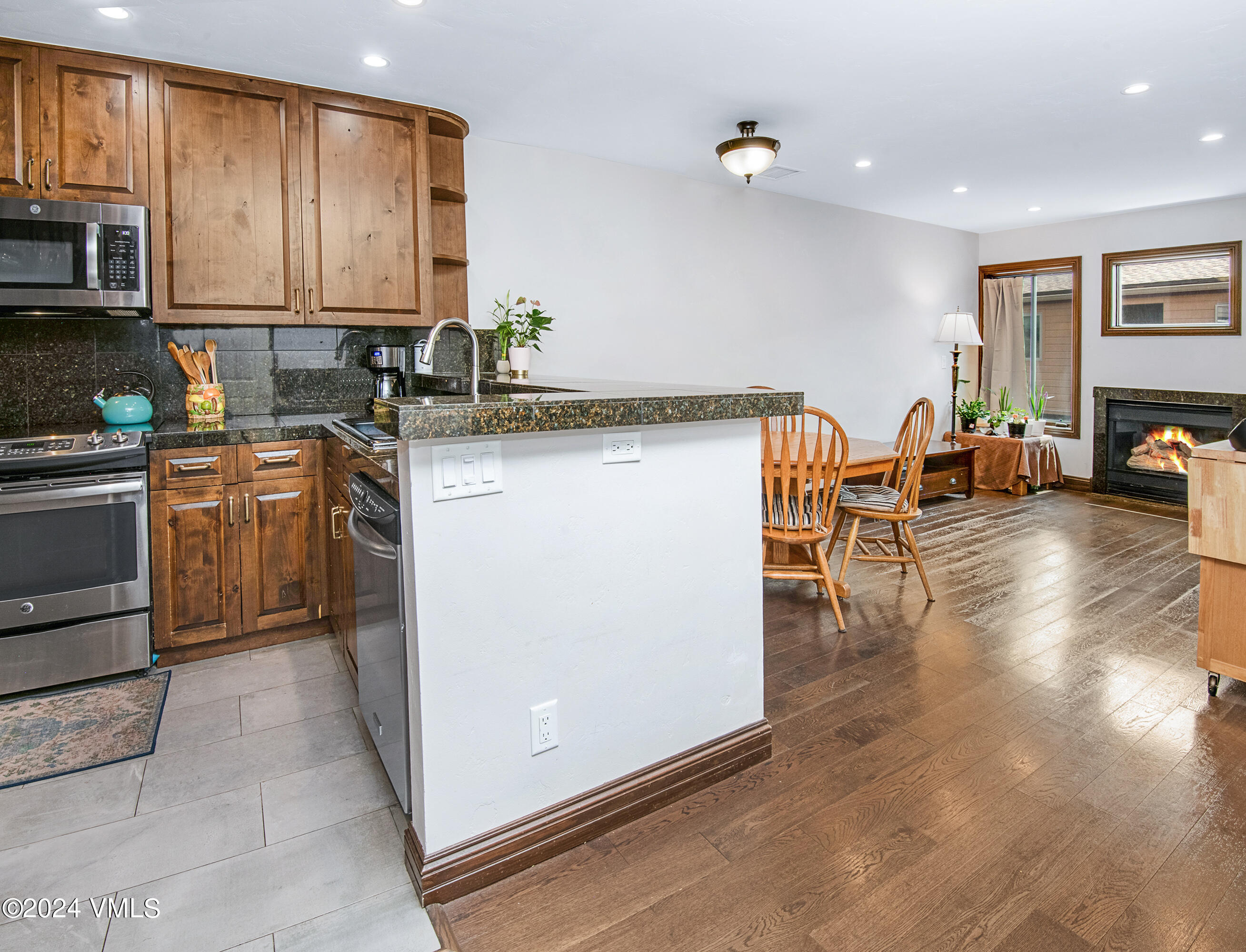 600 Nottingham Road, Unit 5 Avon, CO 81620 - Photo 8 of 13 a kitchen with stainless steel appliances granite countertop a stove top oven a sink a dining table and chairs with wooden floor