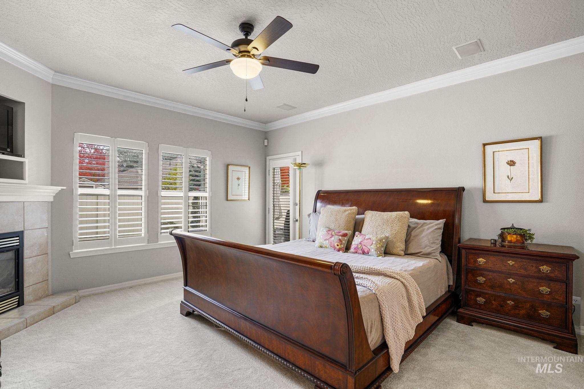 5790 North Wellspring Way Boise, ID 83713 - Photo 18 of 41 Bedroom with a textured ceiling, ornamental molding, a fireplace, carpet, and ceiling fan