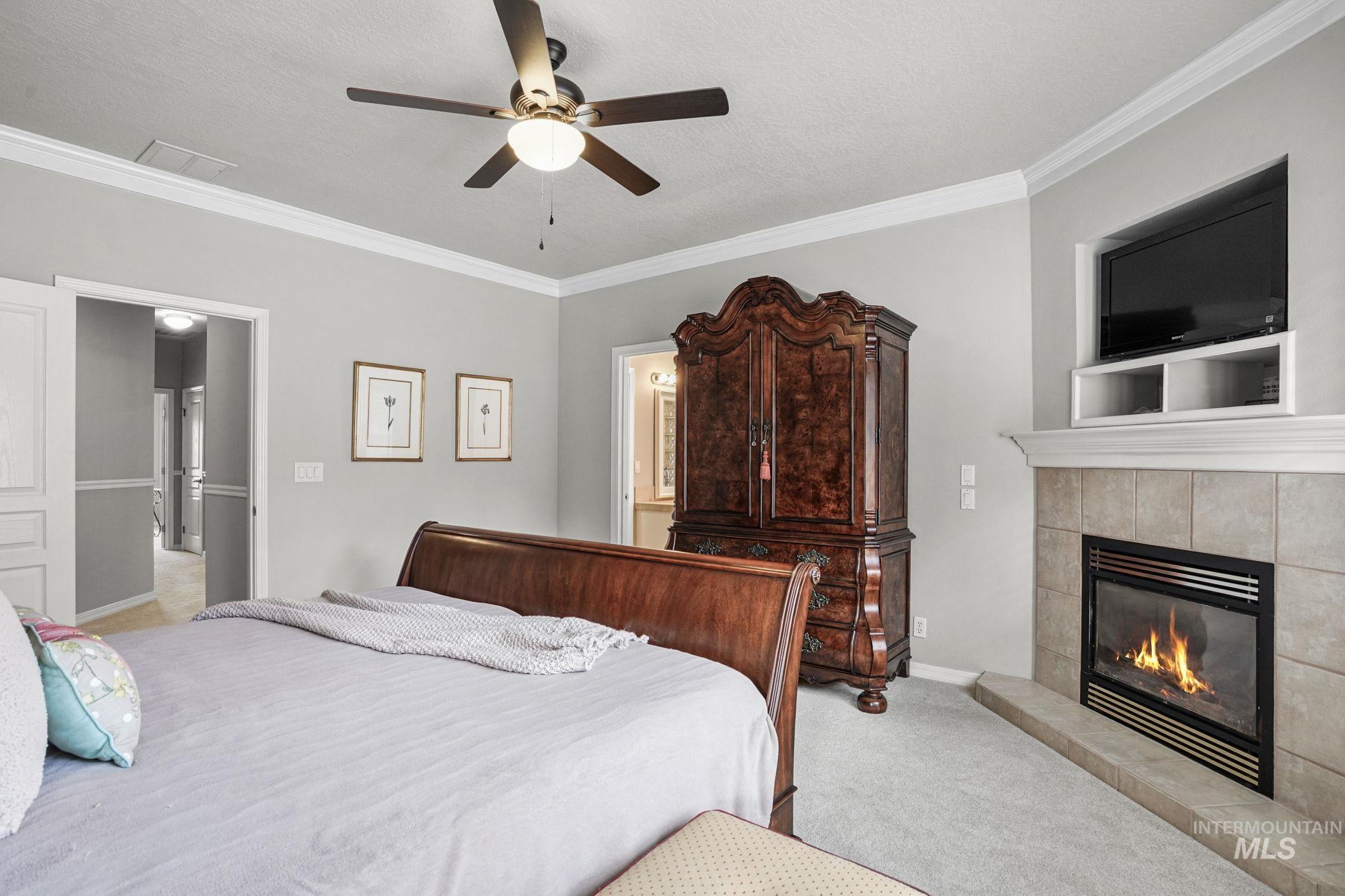 5790 North Wellspring Way Boise, ID 83713 - Photo 19 of 41 Carpeted bedroom featuring crown molding, ceiling fan, a textured ceiling, and a fireplace