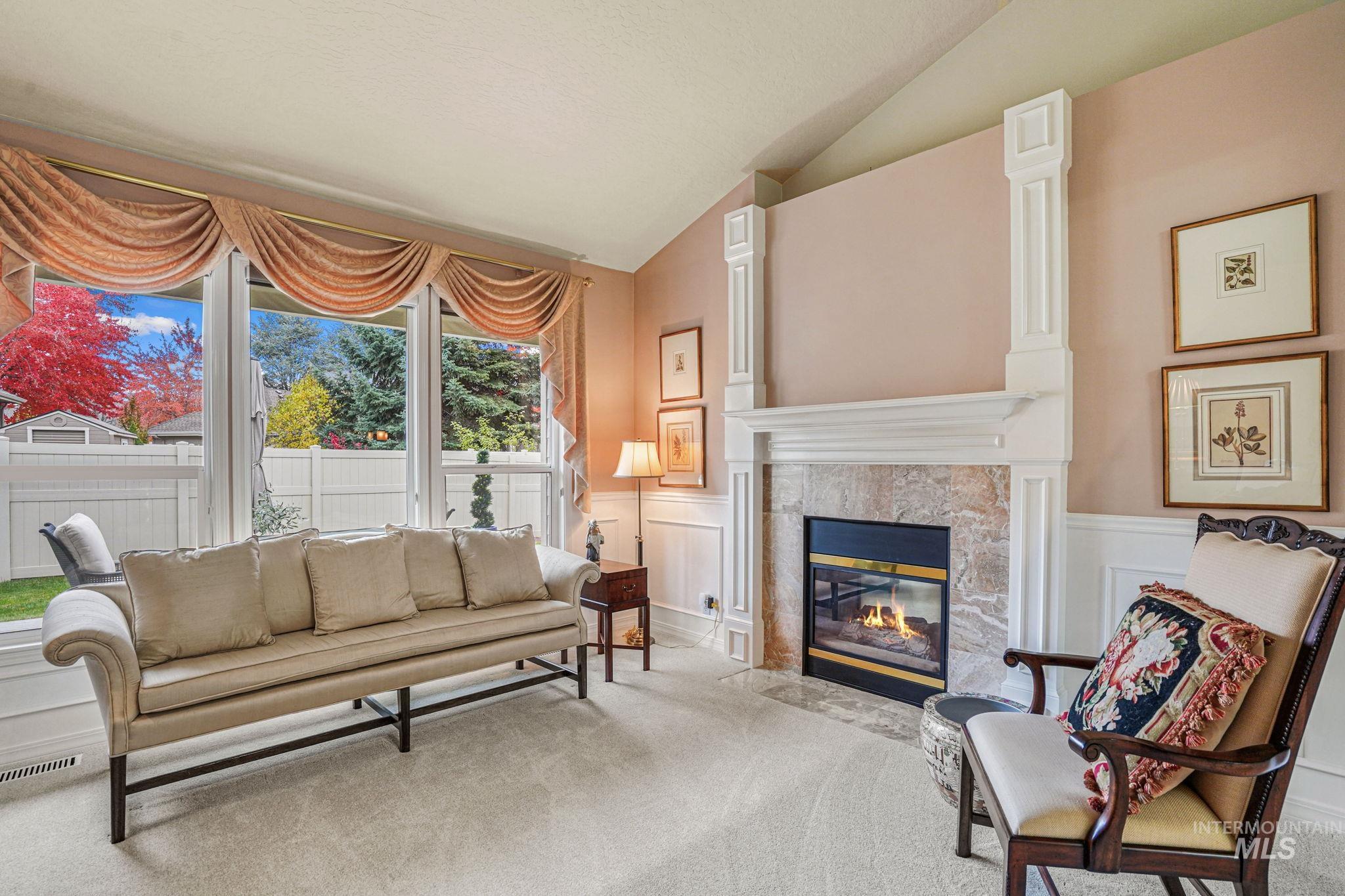 5790 North Wellspring Way Boise, ID 83713 - Photo 31 of 41 Carpeted living room featuring a decorative wall, a wainscoted wall, a fireplace, and vaulted ceiling