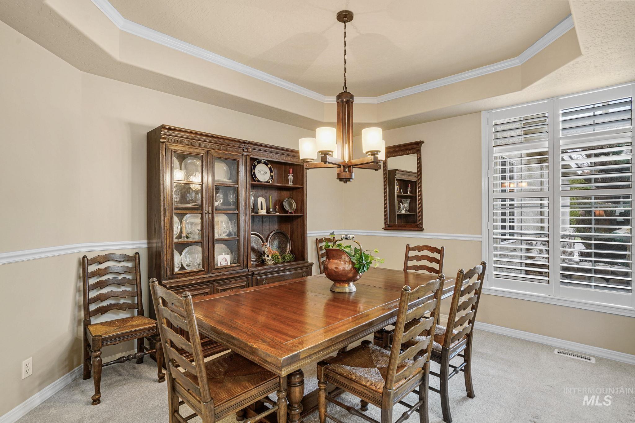 5790 North Wellspring Way Boise, ID 83713 - Photo 32 of 41 Dining room featuring light carpet, ornamental molding, a tray ceiling, and a chandelier