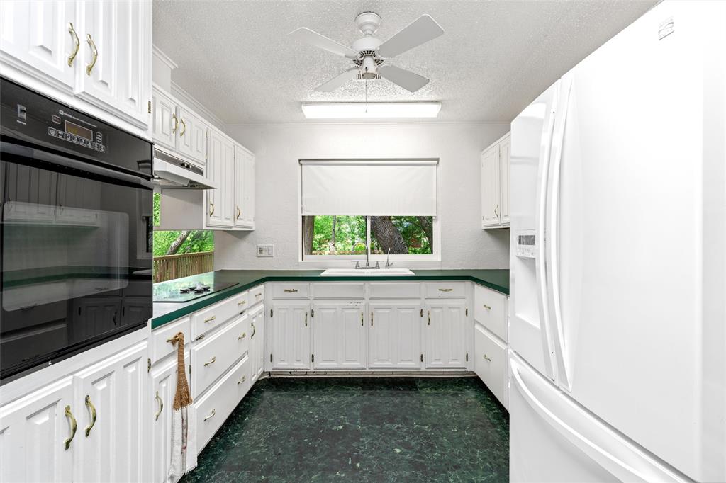 7821 Tallahassee Road Woodway, TX 76712 - Photo 7 of 31 a kitchen with granite countertop white cabinets and white appliances