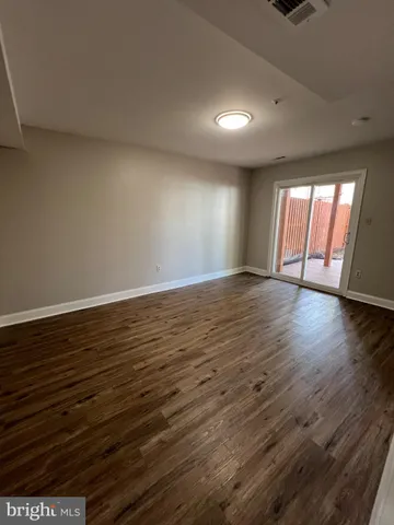 a view of an empty room with wooden floor and window