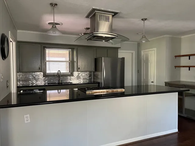 a kitchen with stainless steel appliances granite countertop a sink a stove top oven a counter space and cabinets