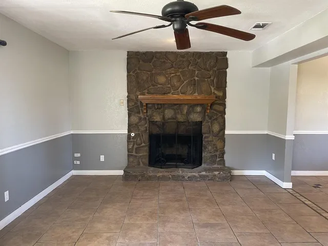 a living room with a fireplace and a ceiling fan