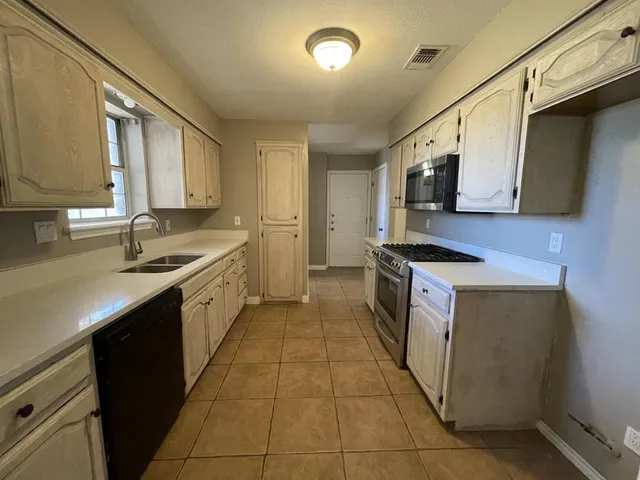 a kitchen with a sink a stove top oven and wooden floor