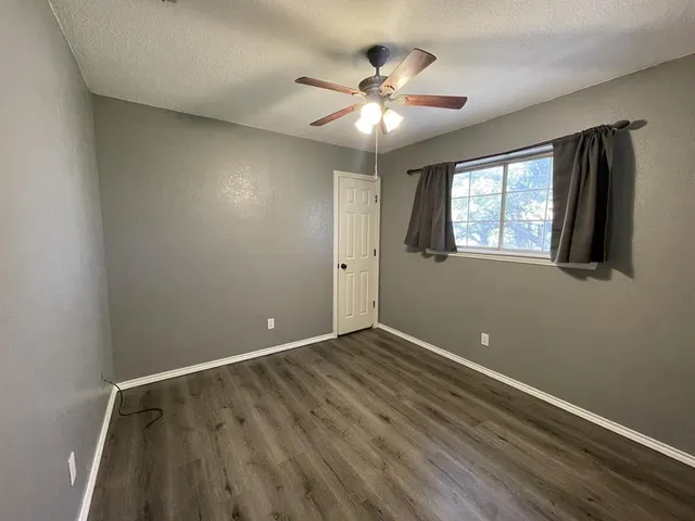 an empty room with windows and fan