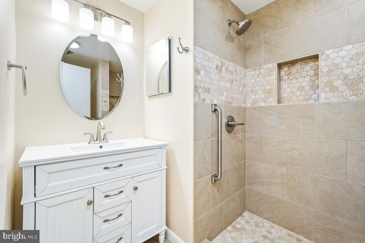 3436 Chiswick Court, Unit 45H Silver Spring, MD 20906 - Photo 28 of 30 a bathroom with a sink a mirror a vanity and shower