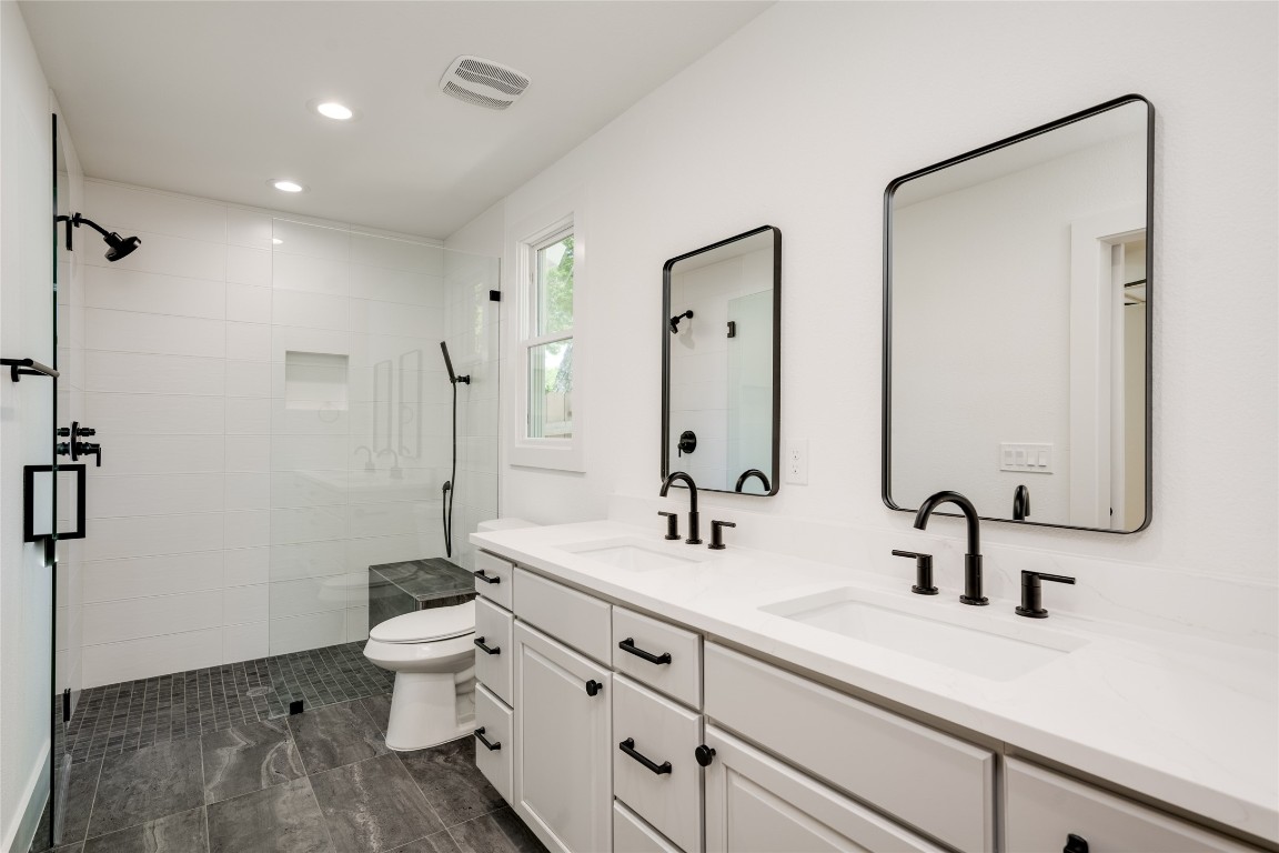 1928 Miles Avenue, Unit 1 Austin, TX 78745 - Photo 24 of 28 a bathroom with a double vanity sink toilet and mirror