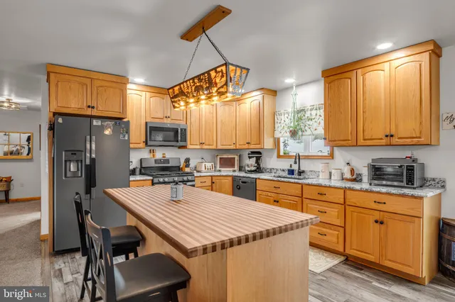 a kitchen with stainless steel appliances a sink a stove a refrigerator cabinets and a dining table