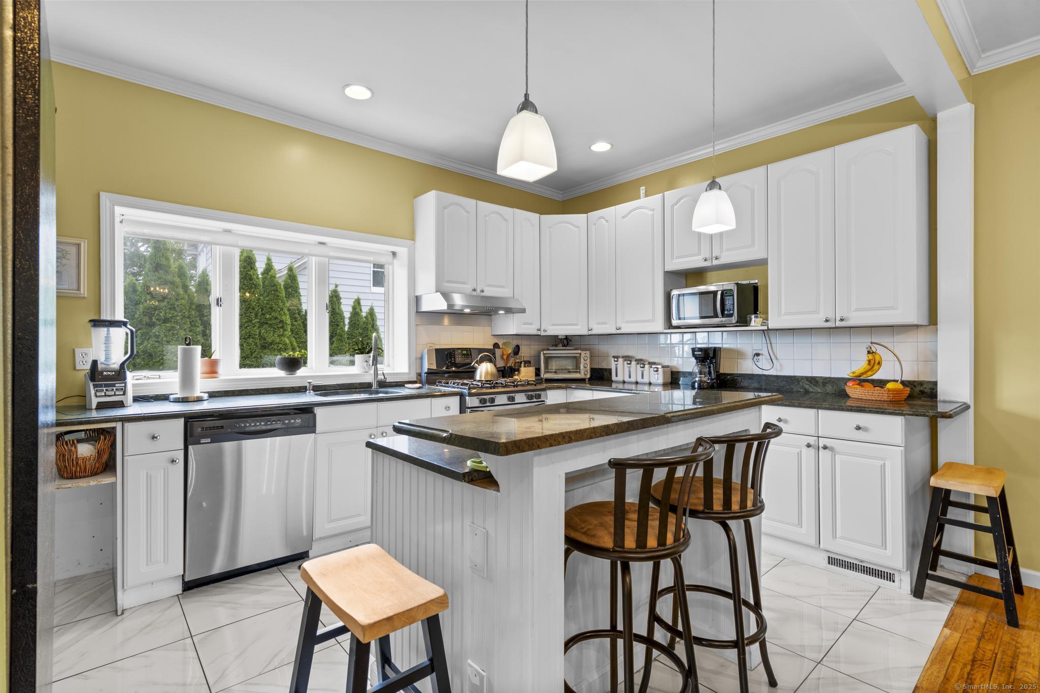 709 Tunxis Hill Road Fairfield, CT 06825 - Photo 8 of 30 a kitchen with stainless steel appliances granite countertop a stove a sink a microwave a dining table and chairs