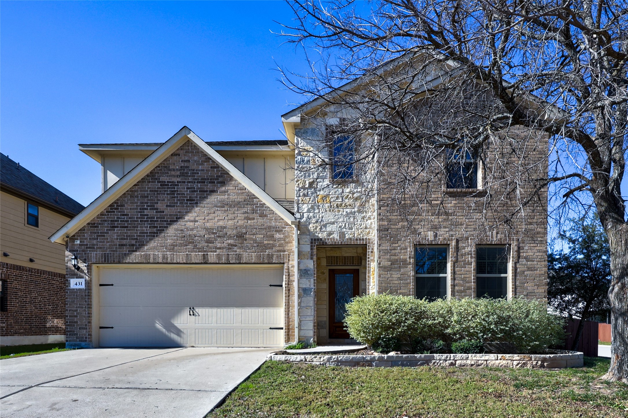 View of front of home featuring an attached garage, driveway, brick siding, and a front yard