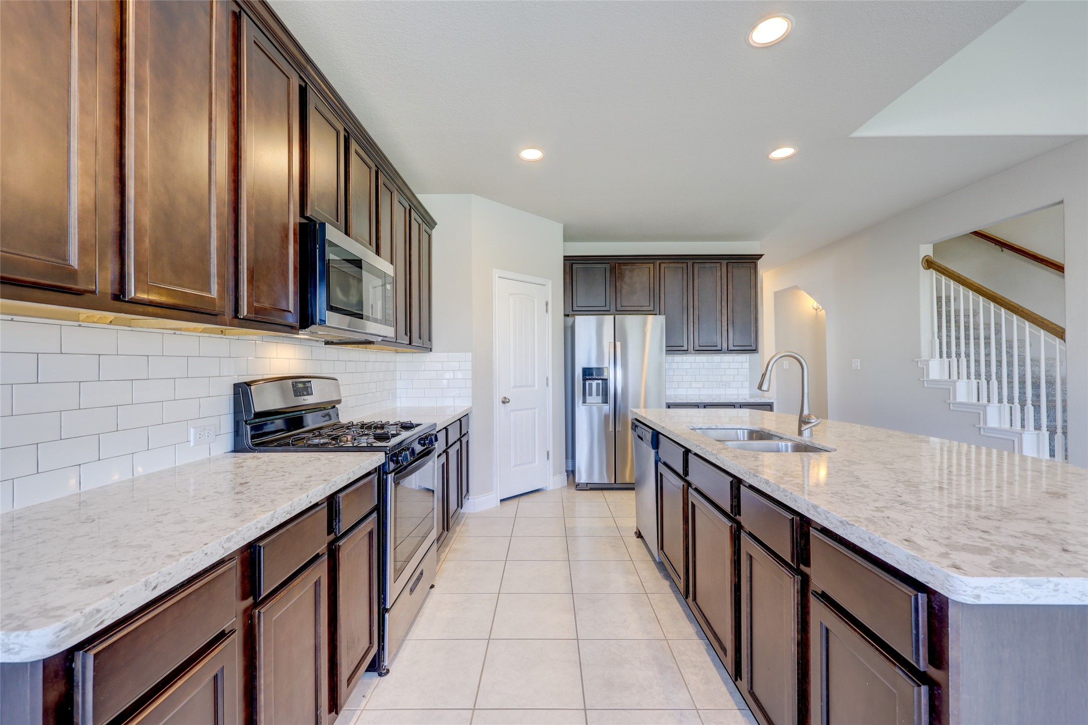 431 Millard Street Georgetown, TX 78628 - Photo 12 of 36 Kitchen with stainless steel appliances, arched walkways, an island with sink, decorative backsplash, and light tile patterned floors