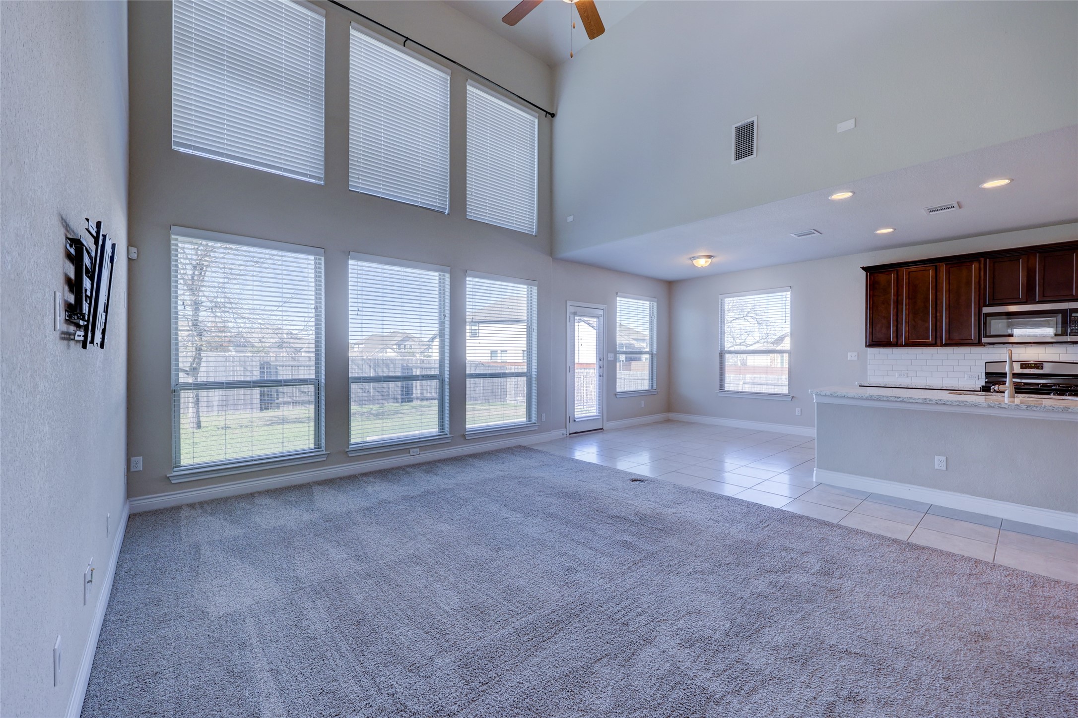 431 Millard Street Georgetown, TX 78628 - Photo 15 of 36 Unfurnished living room with light colored carpet, a ceiling fan, a high ceiling, light tile patterned floors, and recessed lighting