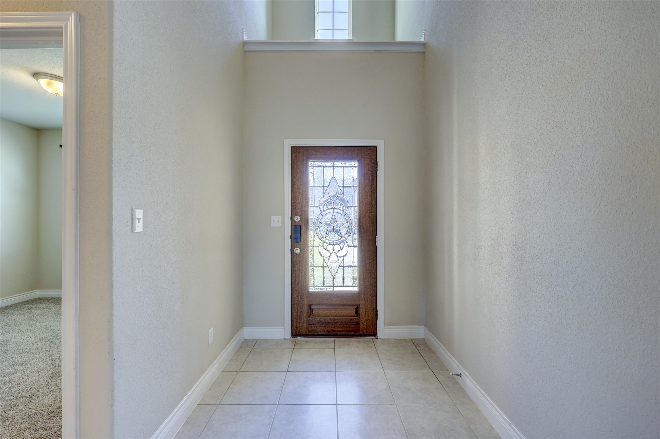 431 Millard Street Georgetown, TX 78628 - Photo 4 of 36 Entryway with healthy amount of natural light, a textured wall, a high ceiling, and light tile patterned floors