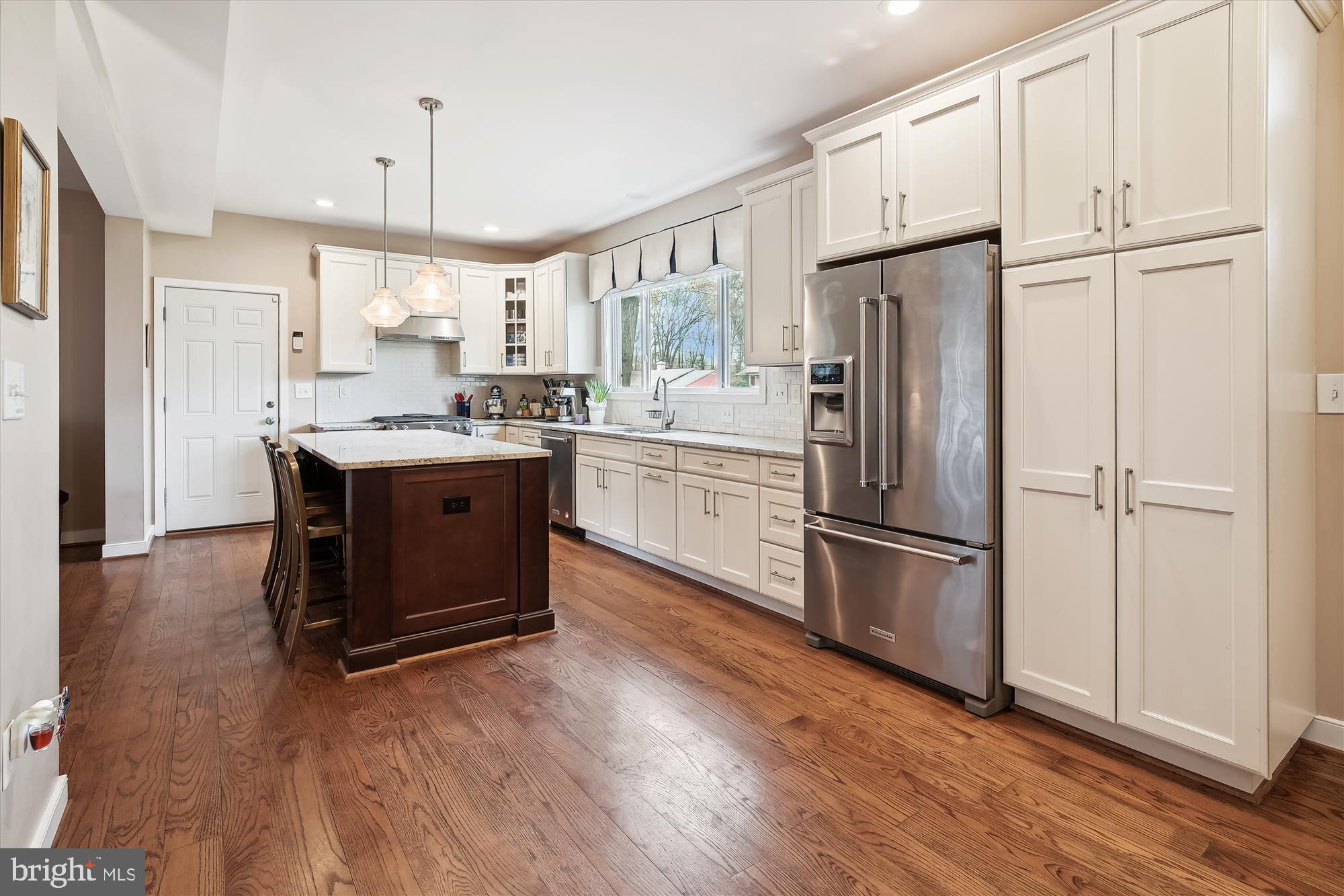 a kitchen with stainless steel appliances granite countertop a refrigerator sink and white cabinets