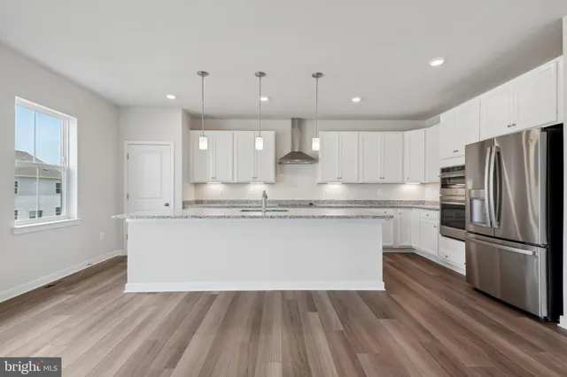 a kitchen with kitchen island wooden floors appliances and cabinets