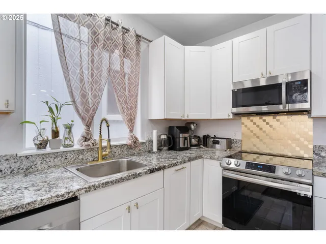 a kitchen with stainless steel appliances granite countertop a sink a stove a microwave and cabinets