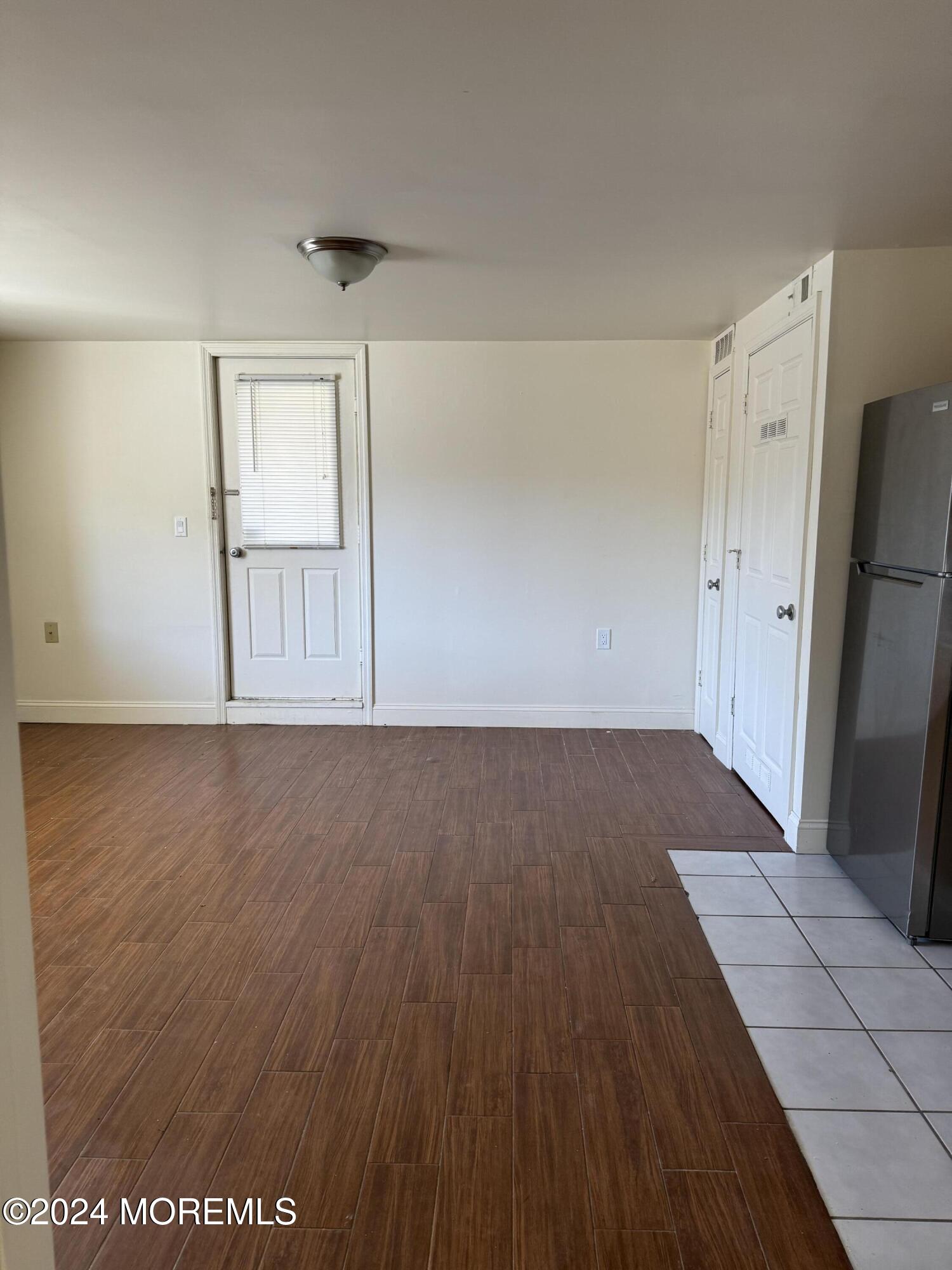 109 2nd Avenue, Unit I Bradley Beach, NJ 07720 - Photo 4 of 8 an empty room with wooden floor and a refrigerator