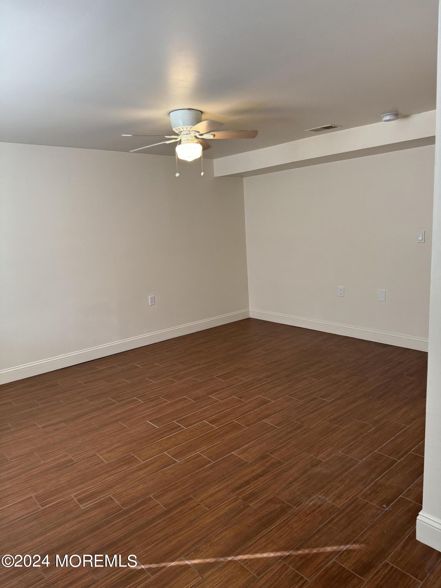 109 2nd Avenue, Unit I Bradley Beach, NJ 07720 - Photo 5 of 8 an empty room with wooden floor and fan