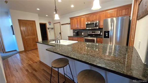 a kitchen with stainless steel appliances granite countertop a refrigerator a stove top oven a sink and dishwasher