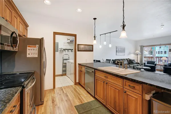 a large kitchen with stainless steel appliances a stove a sink dishwasher and a refrigerator with wooden floor