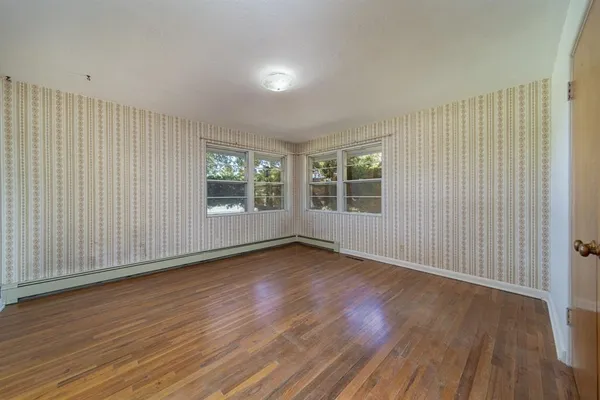 an empty room with wooden floor and windows