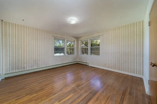 an empty room with wooden floor and windows